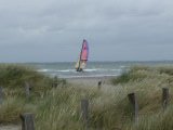 Windsurfer vor einem Strand hinter den Dünen