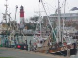 Krabbenkutter im Hafen mit Leuchtturm
